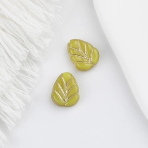 Macro detail of leaf-shaped glass beads in green with delicate golden vein patterns