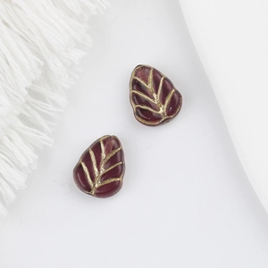Detailed view of two dark red glass leaf beads with gold vein accents for DIY jewelry