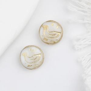 Close-up of duck-shaped Czech glass beads with gold accents on white tassel fabric