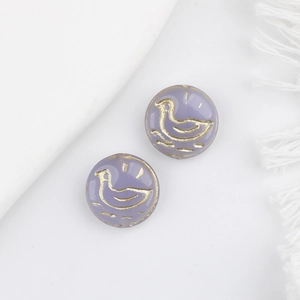 Detailed macro of lavender glass beads with vintage gold duck patterns for jewelry DIY