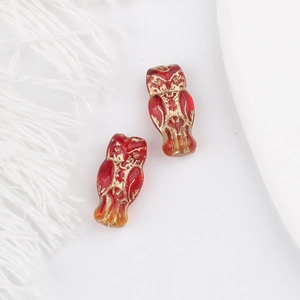 Macro shot of dark red glass owl beads with gold gilding for DIY jewelry making