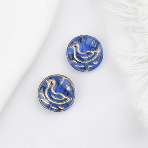 Macro view of two blue Czech glass beads with golden bird patterns for DIY jewelry