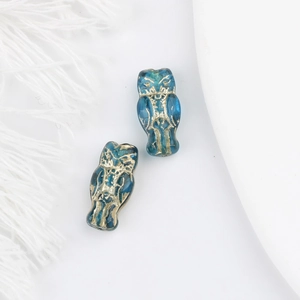 Macro detail of blue Czech glass owl beads with vintage gold embossed engraving