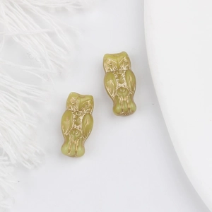Detailed macro view of light green owl glass beads with exquisite gold-painted feather patterns