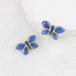 Dettaglio di perline a farfalla in vetro blu con accenti dorati per gioielli DIY
