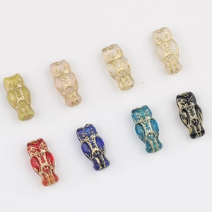 Flat lay of eight colorful Czech glass owl beads with vintage gold gilded details