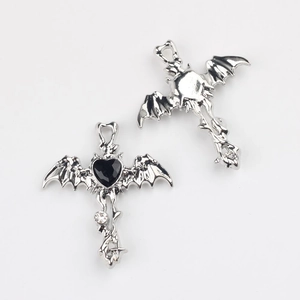 Detail of gothic bat wing cross pendant with black heart stone and silver finish