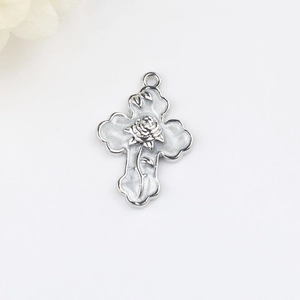 Vue macro d'un pendentif croix en alliage argenté avec rose 3D et émail blanc incrusté