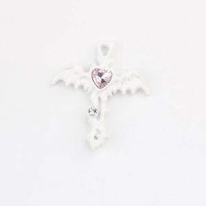 Close-up of white gothic cross pendant with pink heart crystal and bat wing details