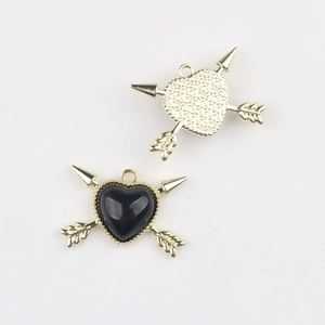 Macro shot of gold alloy and black resin heart charms with cupid arrows for DIY jewelry