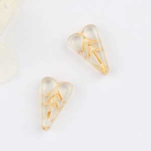 Macro view of transparent heart-shaped glass beads with gold leaf patterns for DIY jewelry