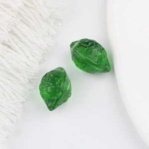 Gros plan de perles en verre vert translucide en forme de noix avec texture pour bijoux DIY