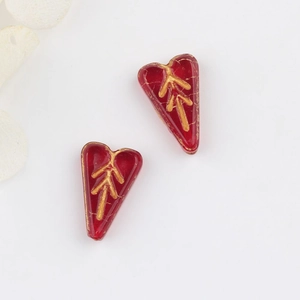 Macro view of vintage red glass heart beads with gold leaf patterns for DIY jewelry