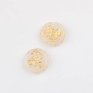 Detailed macro view of two cream Czech glass beads with gold sunflower pattern for DIY jewelry