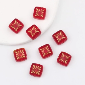 Macro view of 10mm red square Czech glass beads with hand-painted gold firework patterns