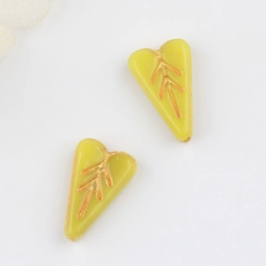 Macro shot of yellow heart-shaped glass beads with vintage gold leaf pattern details