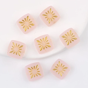 Macro shot of pink translucent square glass beads with gold fireworks pattern for DIY jewelry