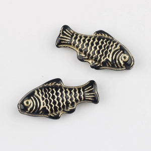 Macro detail of hand-painted black and gold fish glass beads for DIY jewelry making