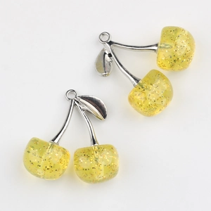 Macro view of cherry fruit charms with translucent yellow resin and gold glitter fill