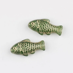 Detailed view of hand-painted green glass fish beads with golden scale texture for DIY jewelry