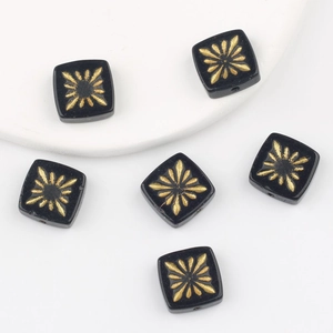 Detail of square glass beads with gold starburst pattern and central through-hole