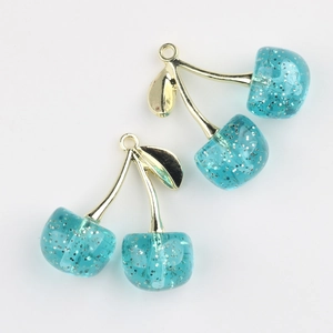 Detail of light blue cherry resin pendants with glitter and gold metal leaf hooks