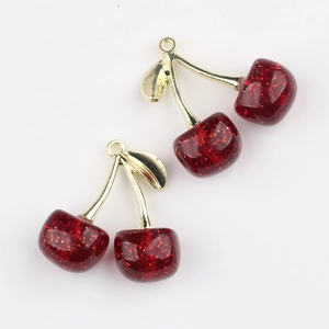 Detailed view of translucent red resin cherry charms with glitter and gold stems