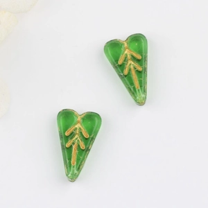 Close-up of translucent green leaf-shaped glass beads with gold-leaf patterns on white