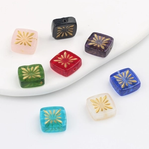 Detail of 10mm square Czech glass beads with hand-painted gold sunburst floral patterns