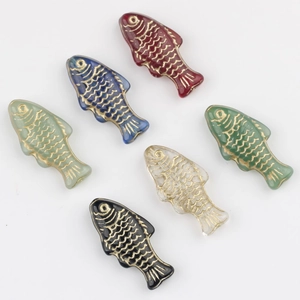 Macro shot of colorful glass fish beads with gold accents for DIY jewelry making