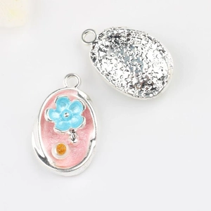 Macro view of alloy pendant featuring pink enamel, blue flower, and star-embossed back