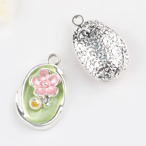 Detail of floral enamel pendant featuring green base, pink flower and star pattern back