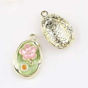 Detailed view of oval floral pendant with green enamel and star-textured gold backing
