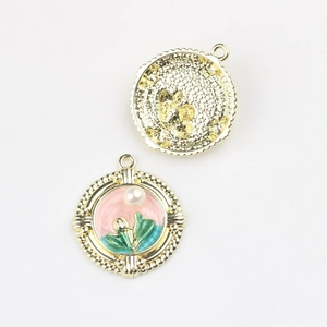 Detailed close-up of pink enamel floral charms with pearl inlay and golden textured back