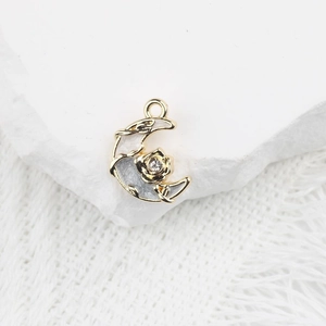 Détail macro du pendentif lune doré avec émail blanc et rose sertie d'un cristal