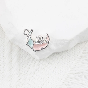 Détail d'un pendentif lune avec rose en émail et cristal en alliage argenté