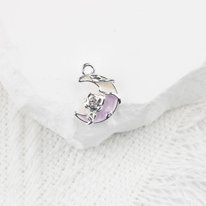 Détail du pendentif lune avec rose et strass sur fond de dentelle blanche et pierre