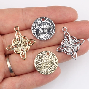 Silver and gold Celtic knot and evil eye pendants held in hand for jewelry DIY