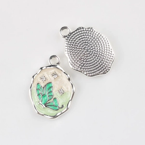 Detail of enamel butterfly pendant with green zircons and textured metal back