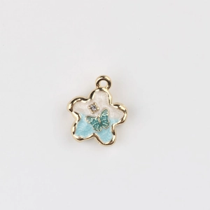 Detail of flower charm with blue enamel, butterfly accent and cubic zirconia stone