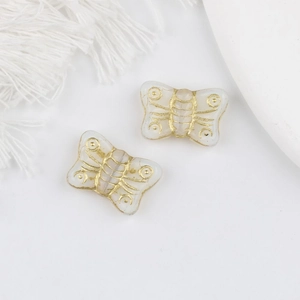 Detailed view of vintage white glass butterfly beads with gold gilded textures for DIY jewelry