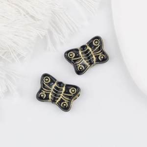 Detail of vintage black and gold butterfly beads with intricate spiral engraved textures