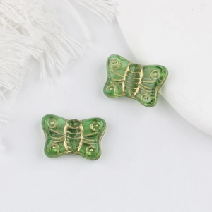 Detailed macro view of green butterfly glass beads with gold gilded textures for jewelry
