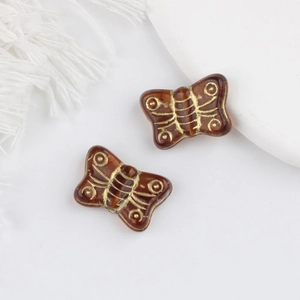 Detail of amber Czech glass butterfly beads with gold gilded patterns for DIY jewelry