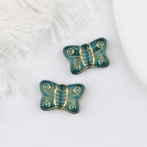 Macro shot of dark green Czech glass butterfly beads with detailed gold leaf gilding