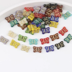Detailed view of colorful butterfly glass beads with gold engraved lines for DIY jewelry