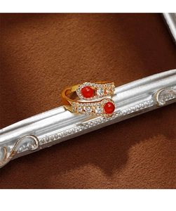 Detailed macro shot of a gold snake ring with red stones and sparkling zircon pavé