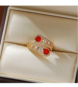 Macro shot of gold snake-style bypass ring with red agate and shimmering zircon accents