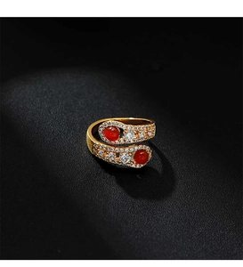 Macro shot of gold snake-shaped bypass ring with red agate and zircon on black leather