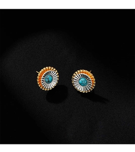 Détail de boucles d'oreilles fleur turquoise avec bords dorés sur fond en cuir noir